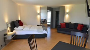 Una habitación de hotel moderna con una cama, un sofá, una mesa de comedor y un televisor montado en la pared.