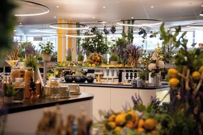 A modern kitchen with a central island, various kitchen appliances, and potted plants. - Hotel Egerkingen (Egerkingen)