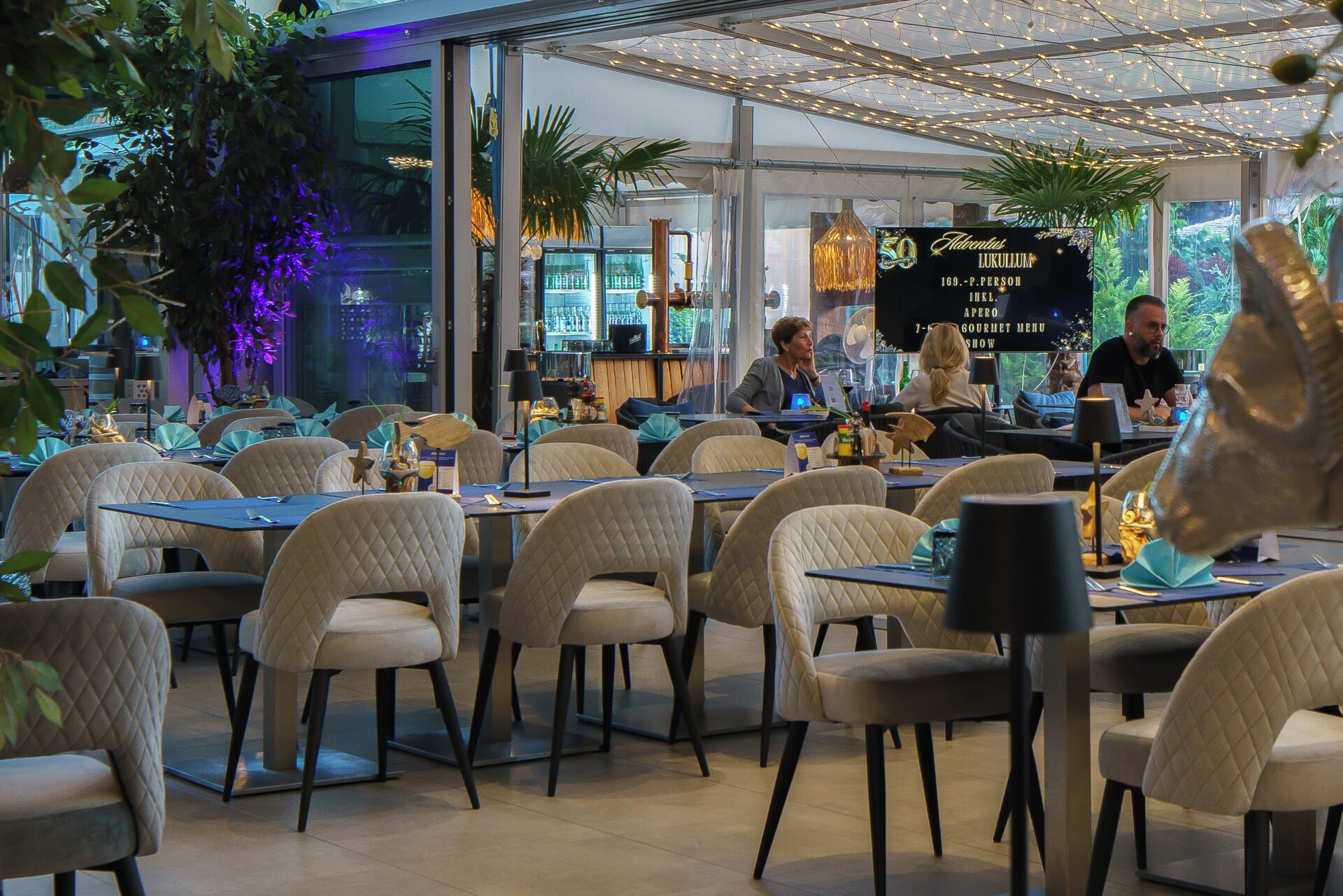 Un ristorante con tavoli e sedie, un'area bar e un cartello pubblicitario di uno spettacolo.