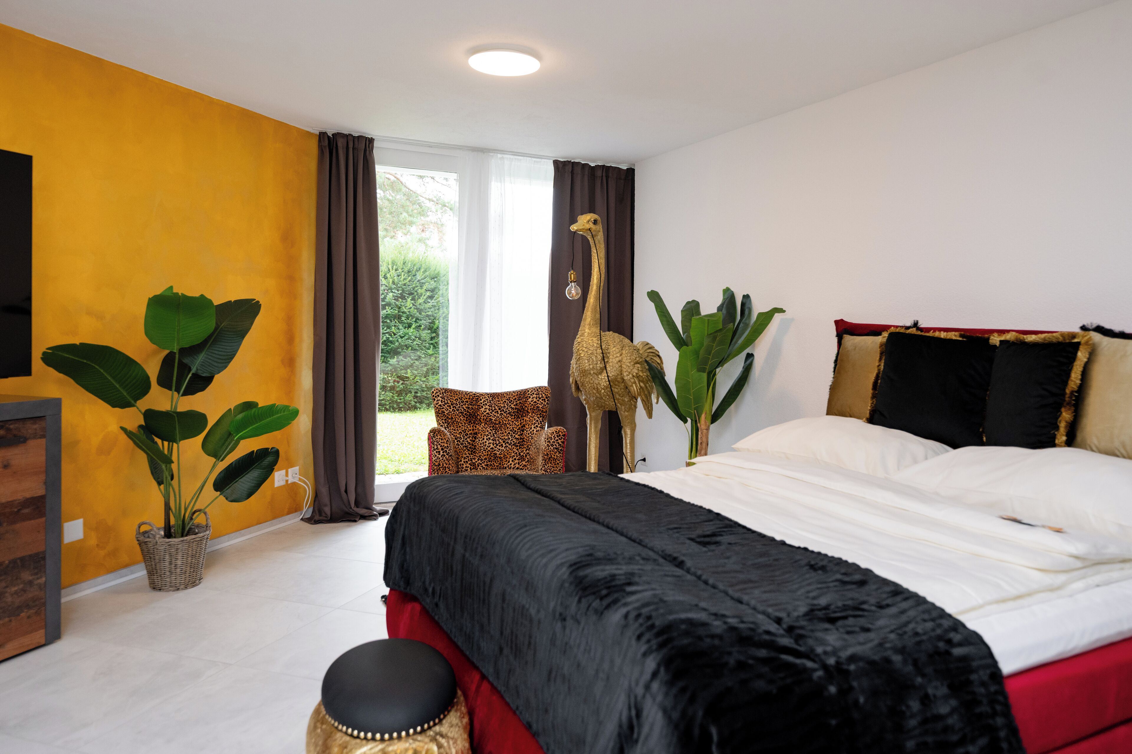 Une chambre à coucher avec un lit, une chaise, une plante en pot et une statue de girafe.