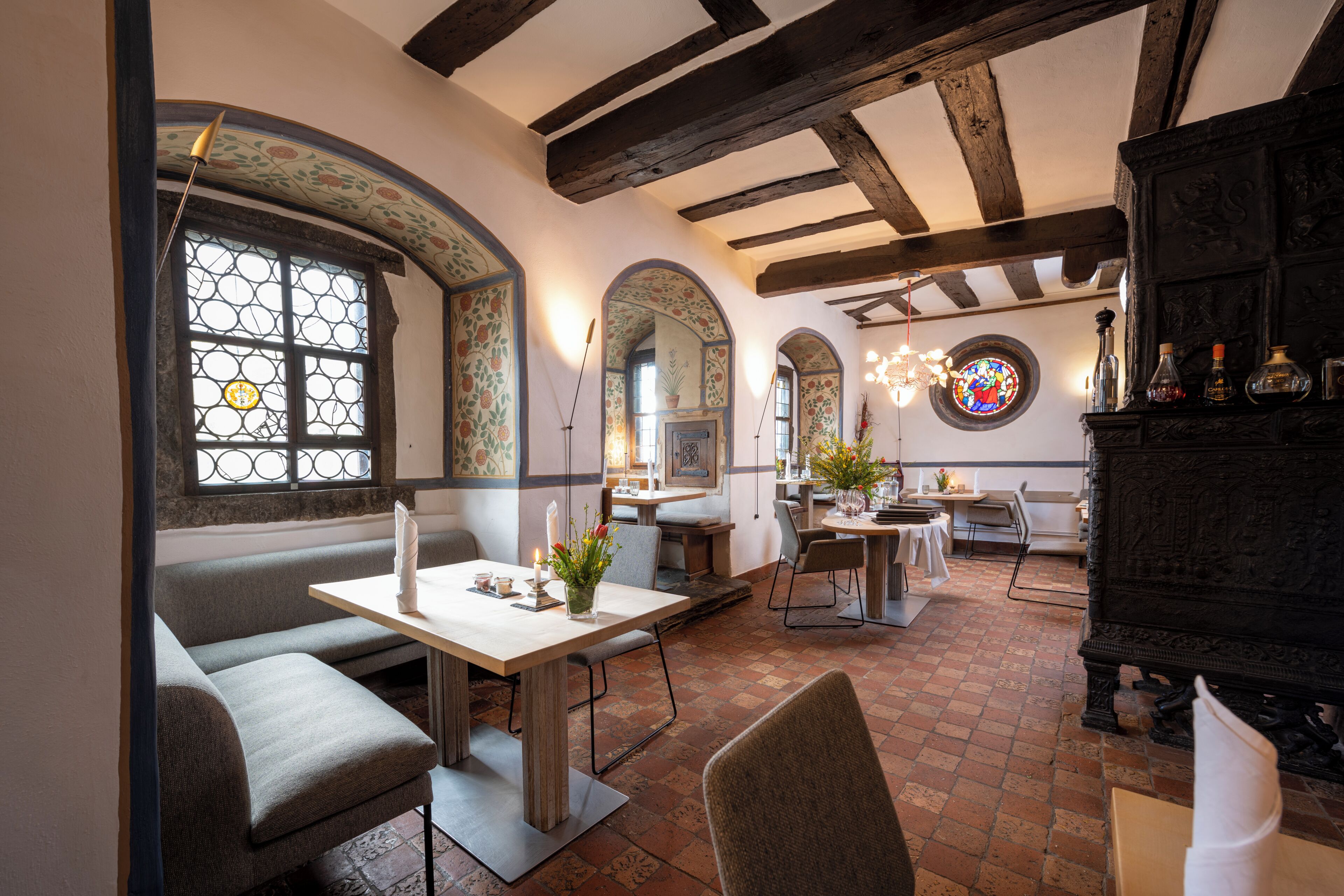 Un restaurante con suelo de ladrillo, vigas de madera y una ventana de vitral.