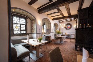 Un restaurante con suelo de ladrillo, vigas de madera y una ventana de vitral.