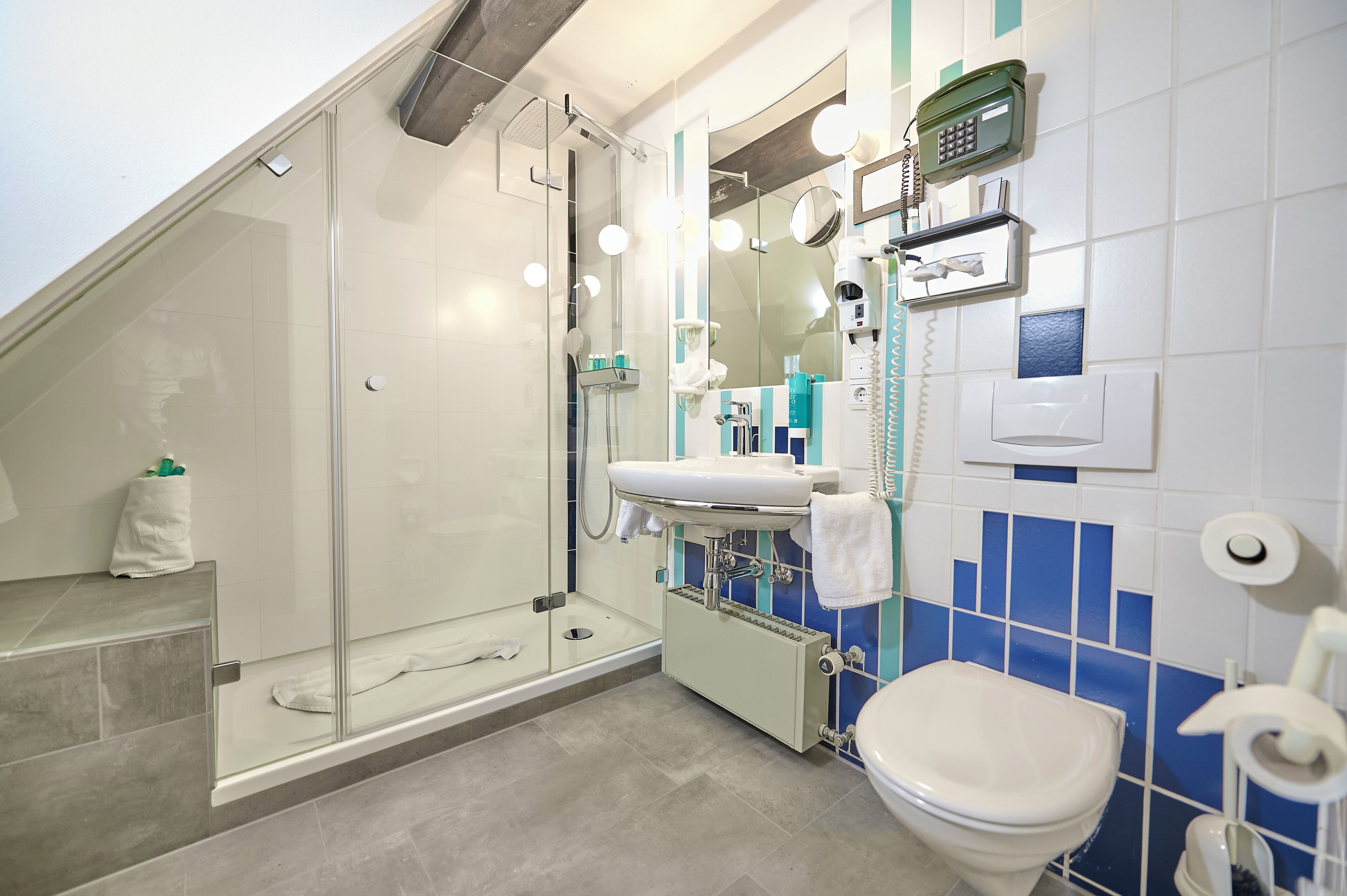 A modern bathroom with a glass-enclosed shower, a sink with a mirror, and a toilet.