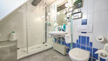 A modern bathroom with a glass-enclosed shower, a sink with a mirror, and a toilet.