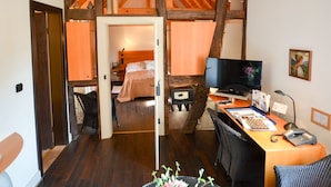 Un dormitorio con techo de madera, una cama, un escritorio con ordenador y una silla.
