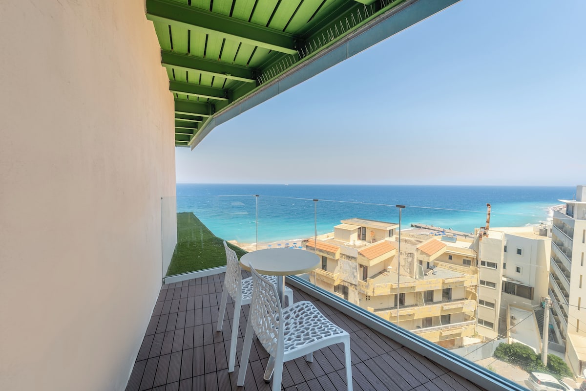 A balcony with a view of the sea and buildings.