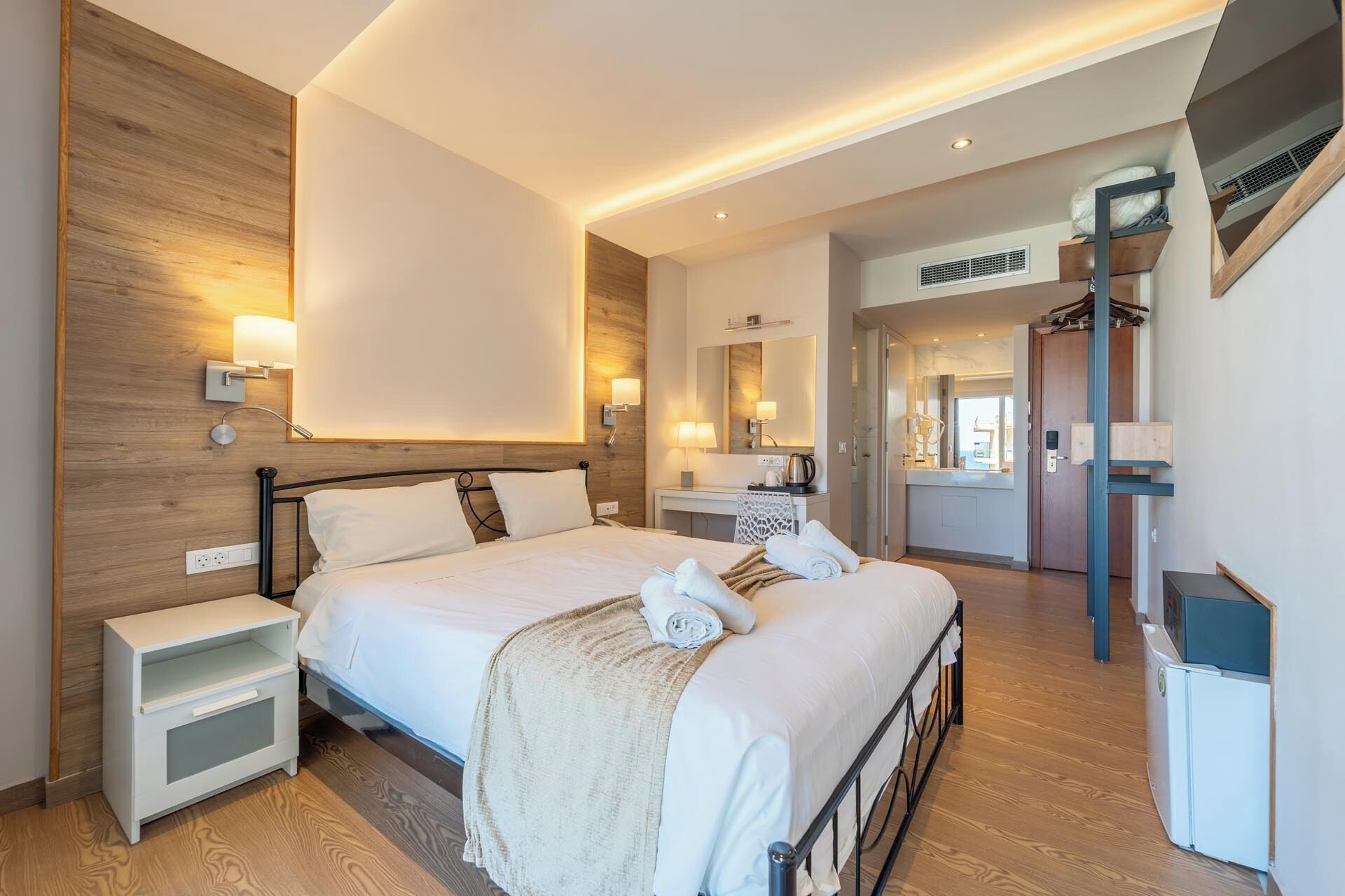 Ein modernes Hotelzimmer mit einem großen Bett, Nachttischen, einem Schreibtisch und einem Spiegel.