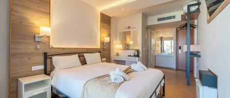 Ein modernes Hotelzimmer mit einem großen Bett, Nachttischen, einem Schreibtisch und einem Spiegel.