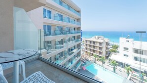 Un hotel moderno con varios balcones, piscina y vista al mar.