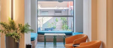 Un interior moderno con una zona de estar, ventanas amplias y una planta en maceta.