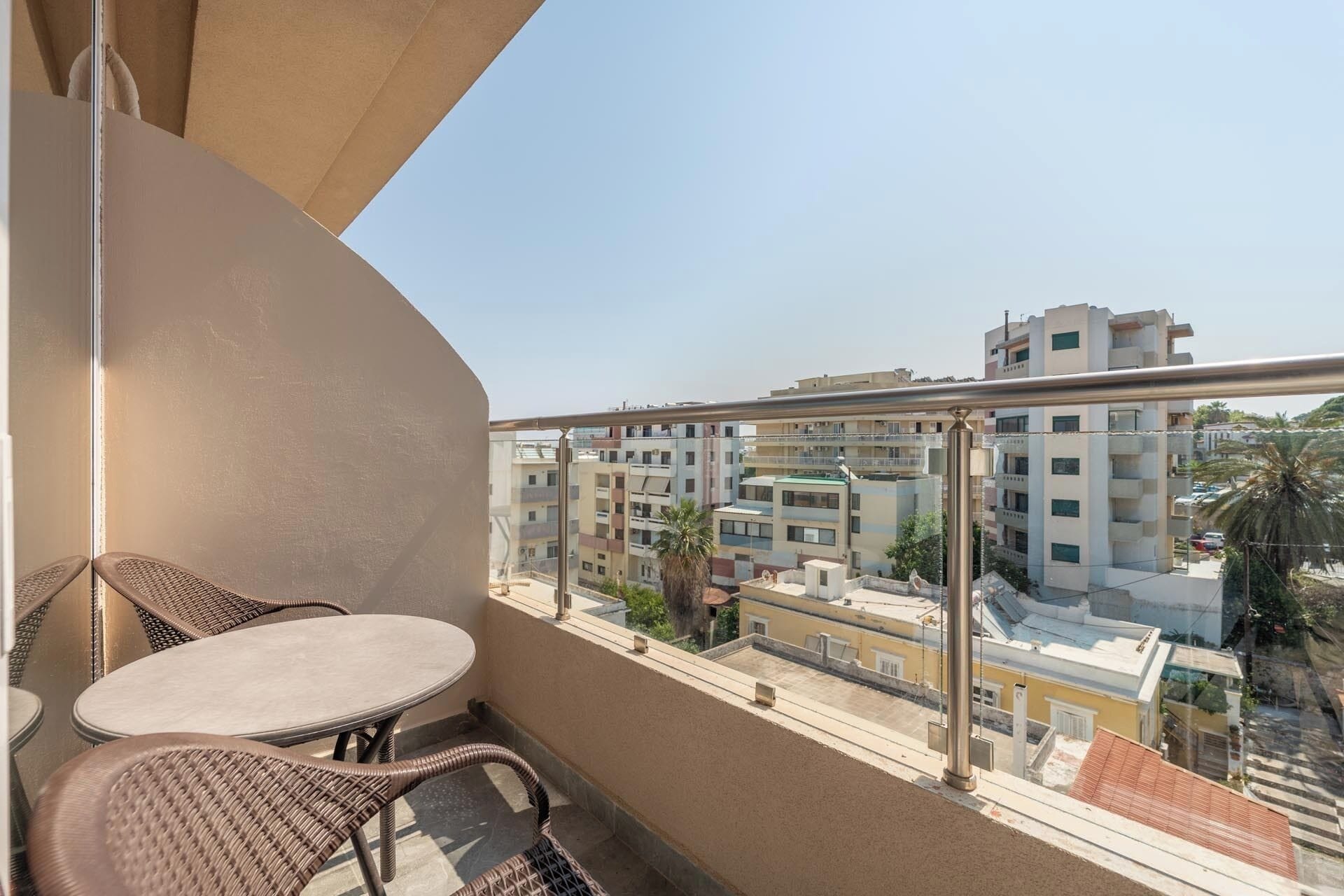 Ein Balkon mit Korbmöbeln und Blick auf mehrstöckige Gebäude.