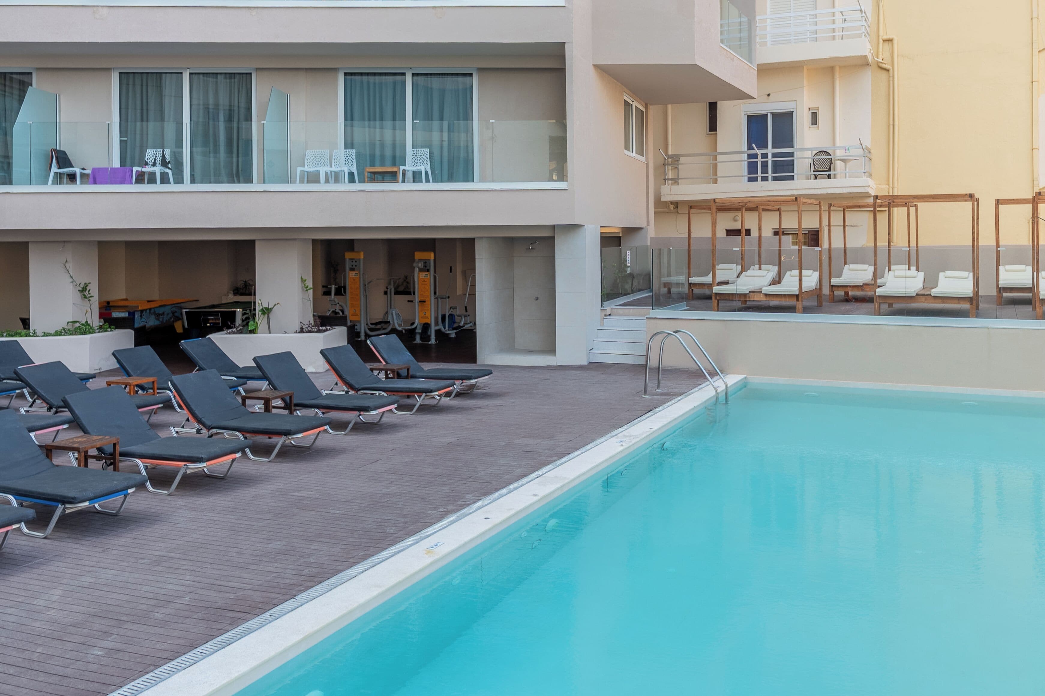 A poolside area with lounge chairs and a pool.