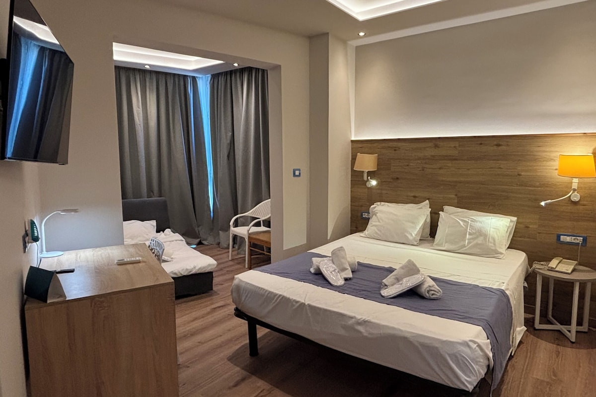 Une chambre d’hôtel avec un lit, une table de chevet, une chaise et un bureau avec une lampe.
