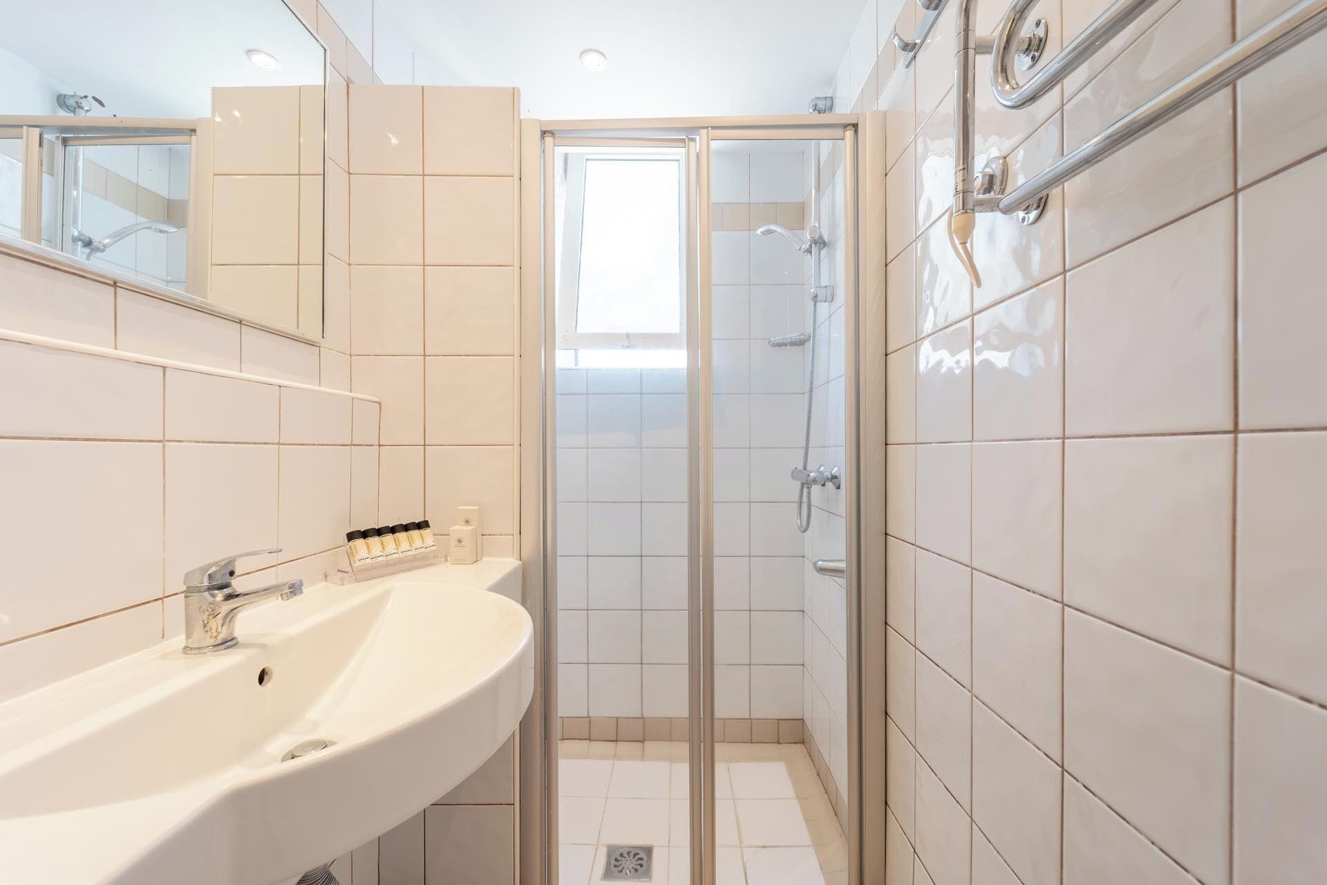 Une salle de bain moderne avec un lavabo blanc, un miroir et un espace douche.