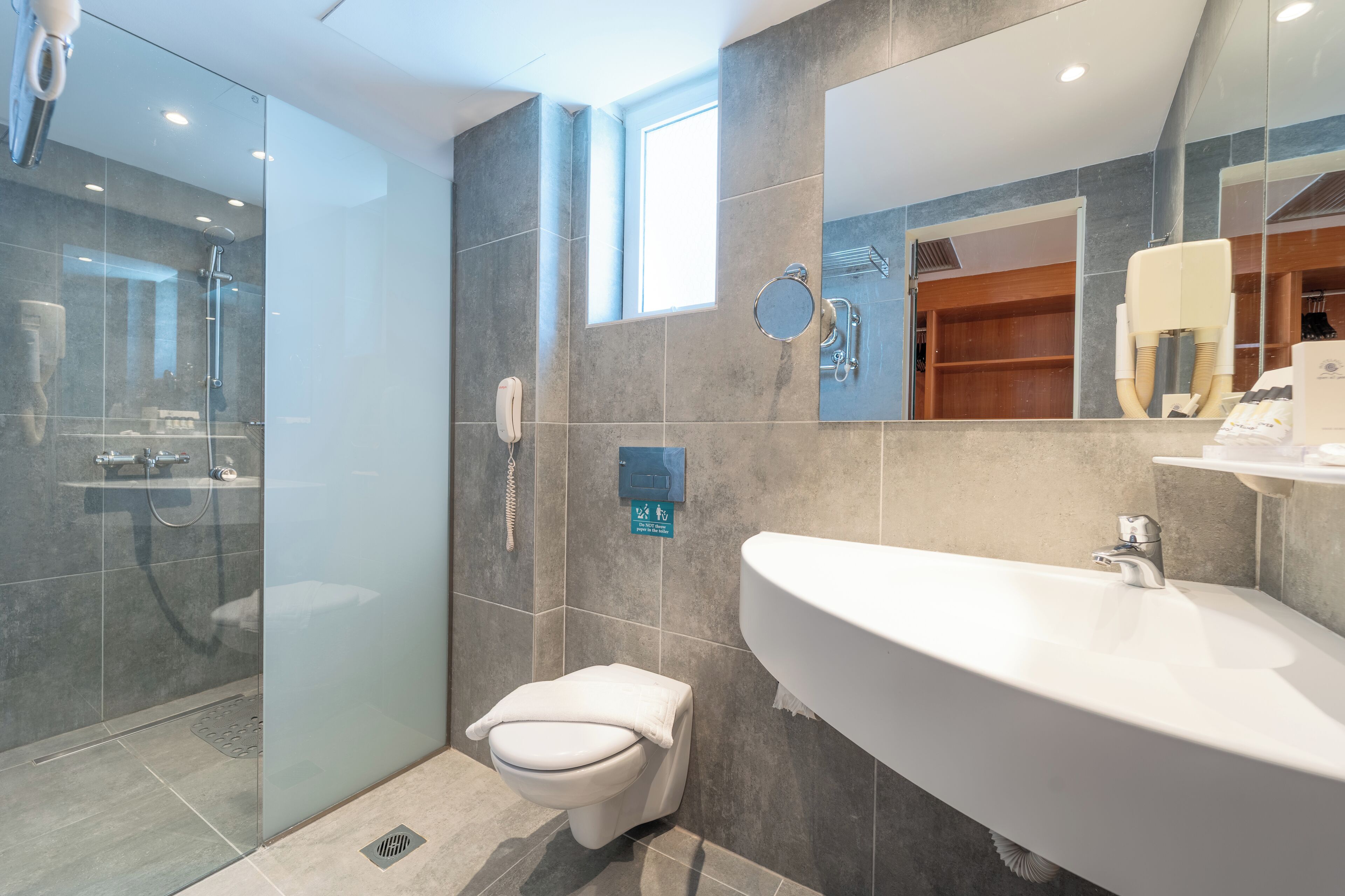 A modern bathroom with a glass-enclosed shower, a toilet, and a large sink.