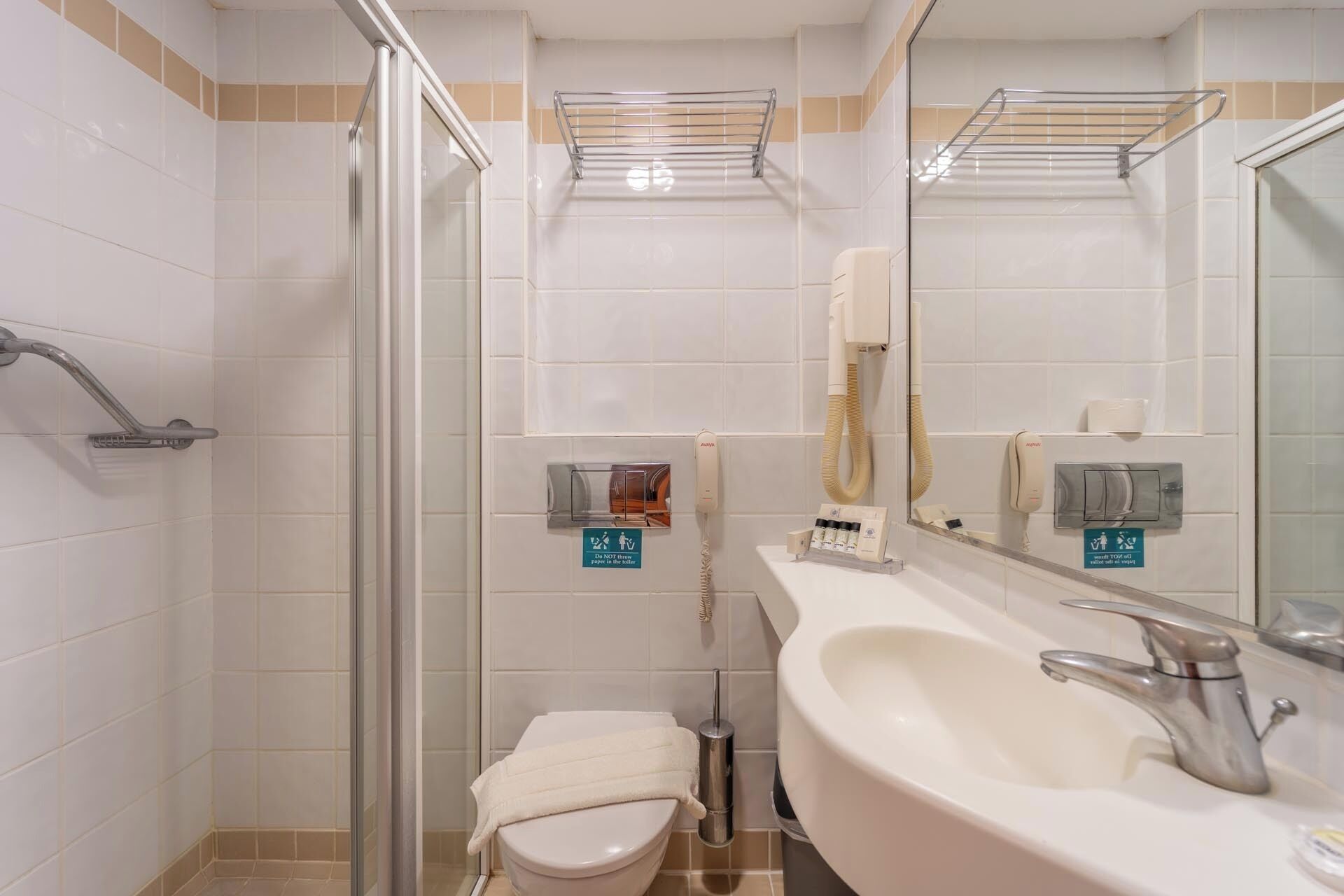A modern bathroom with a glass shower enclosure, a white sink, and a toilet.