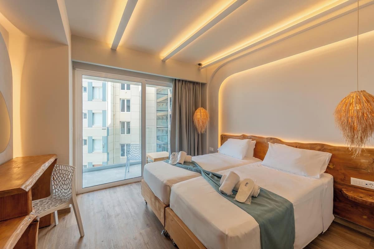 A hotel room with a large window, a bed, a desk, and a chair.