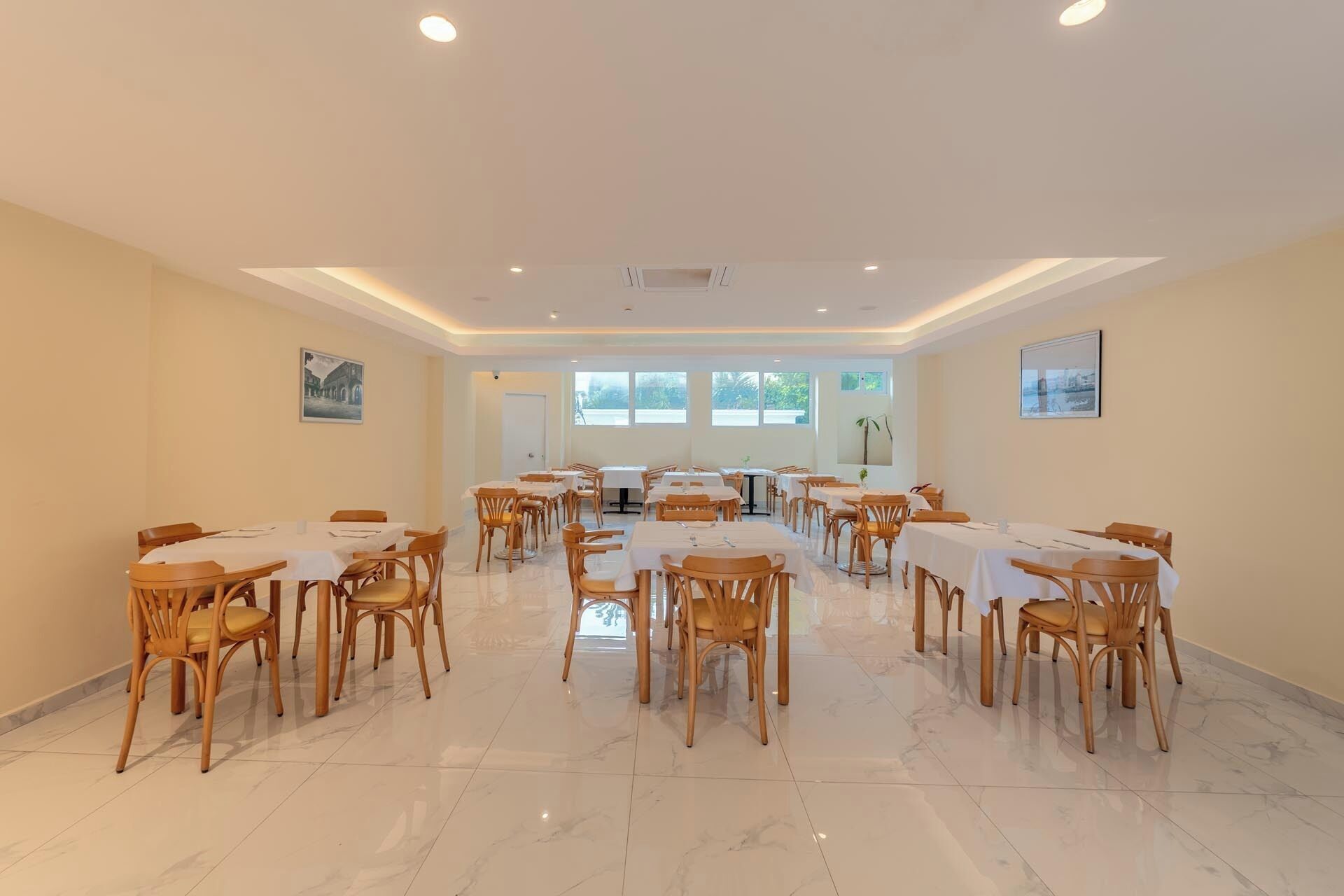 A spacious dining area with multiple tables and chairs, large windows, and a clean, modern design.