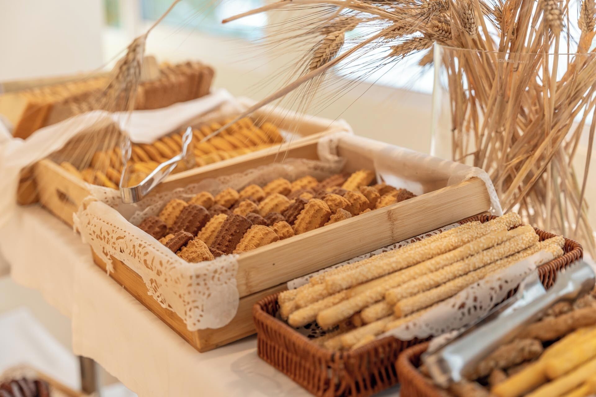 Diversa variedad de panes y pasteles expuestos en cestas de madera sobre una mesa.