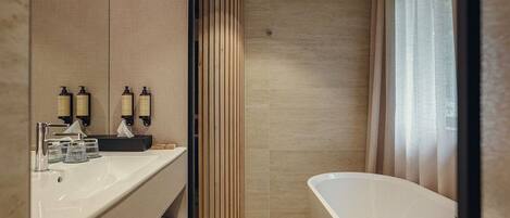 A modern bathroom with a bathtub, a vanity with a mirror, and two bottles of shampoo.