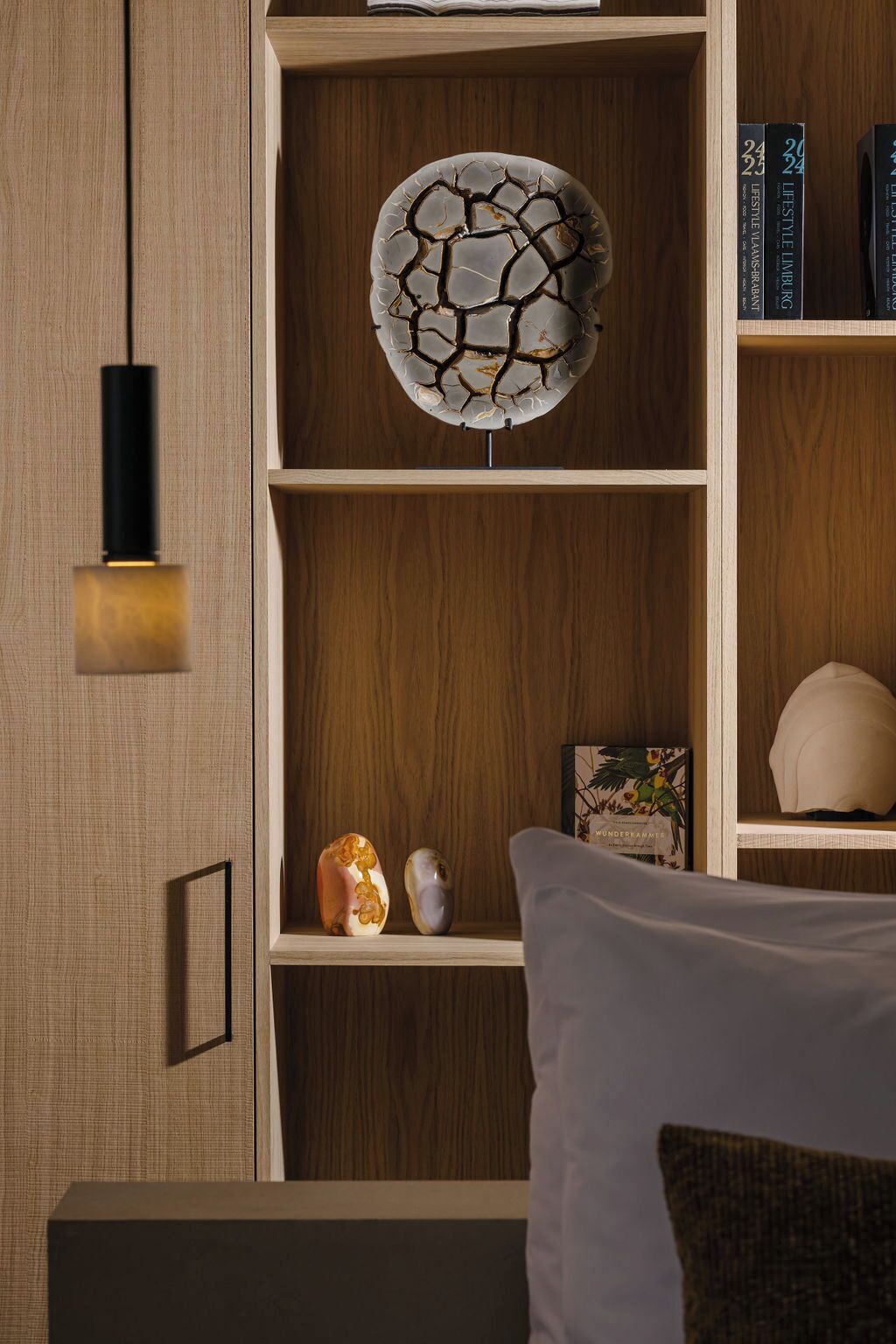 Un dormitorio moderno con una estantería de madera, un adorno en la pared y una lámpara de noche.