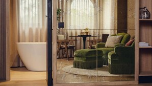 Un baño moderno con una bañera independiente, un sofá tapizado en verde y una mesa redonda con sillas.