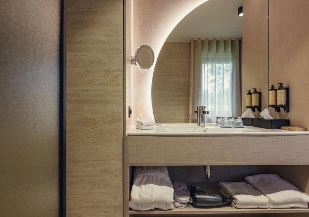 A modern bathroom with a large mirror, a sink, and a towel rack.