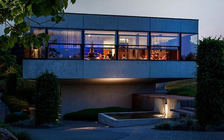 A modern building with large windows and a pool area.