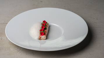 En hvid tallerken med en enkelt spise, muligvis en dessert, på en neutral overflade.