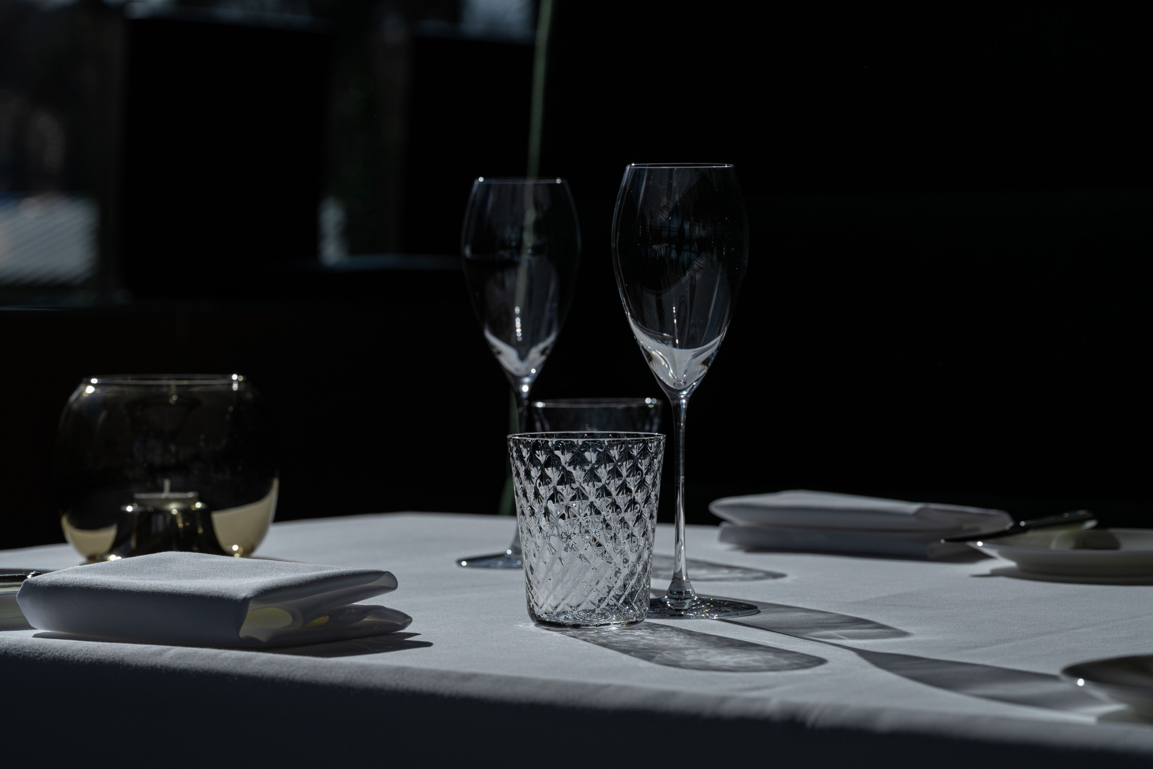 Ein Tisch ist gedeckt mit zwei Weingläsern, einem Wasserglas und einer Serviette.