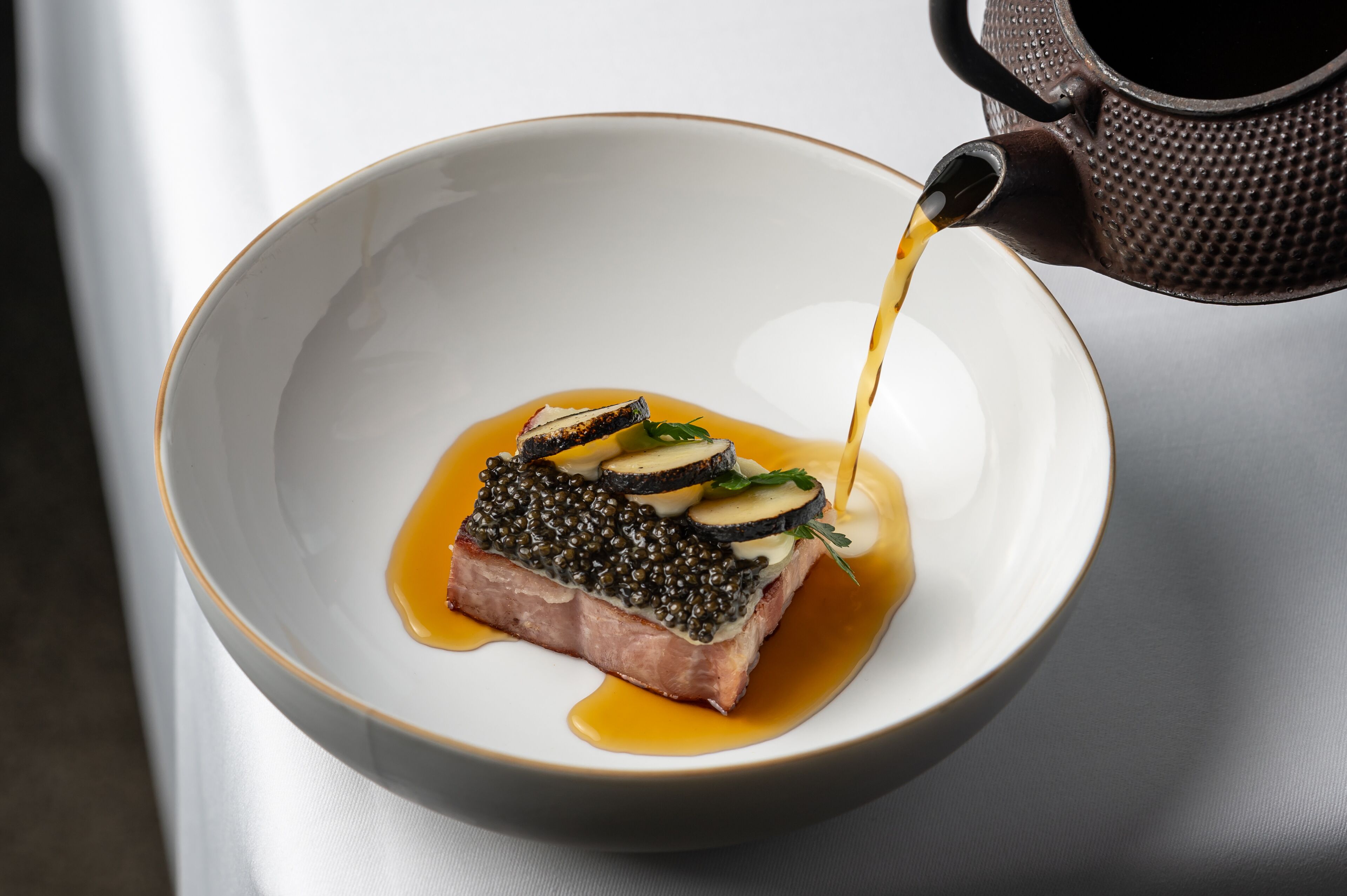 A dish with salmon, caviar, and vegetables in a bowl.