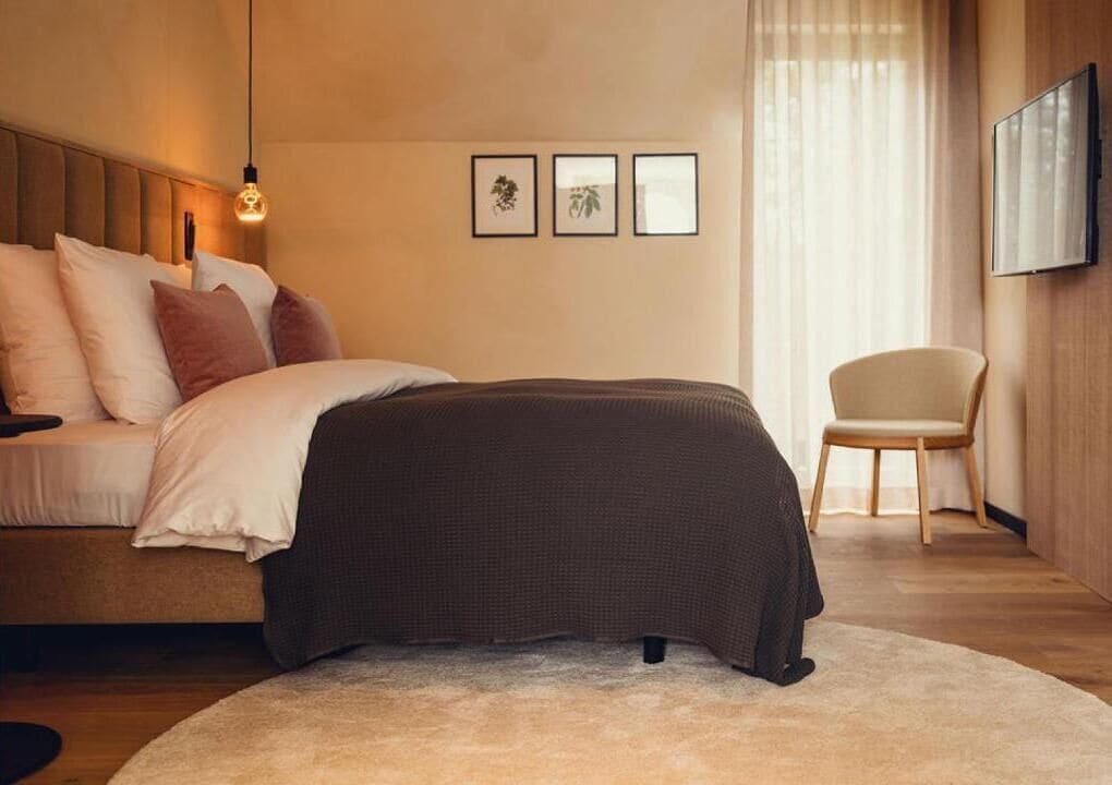 Ein Schlafzimmer mit einem Bett, einem Sessel und gerahmten Bildern an der Wand.