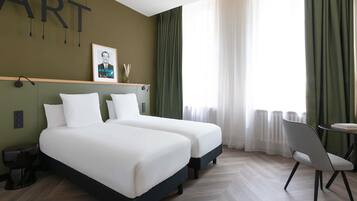 A hotel room with two beds, a desk, and a chair.