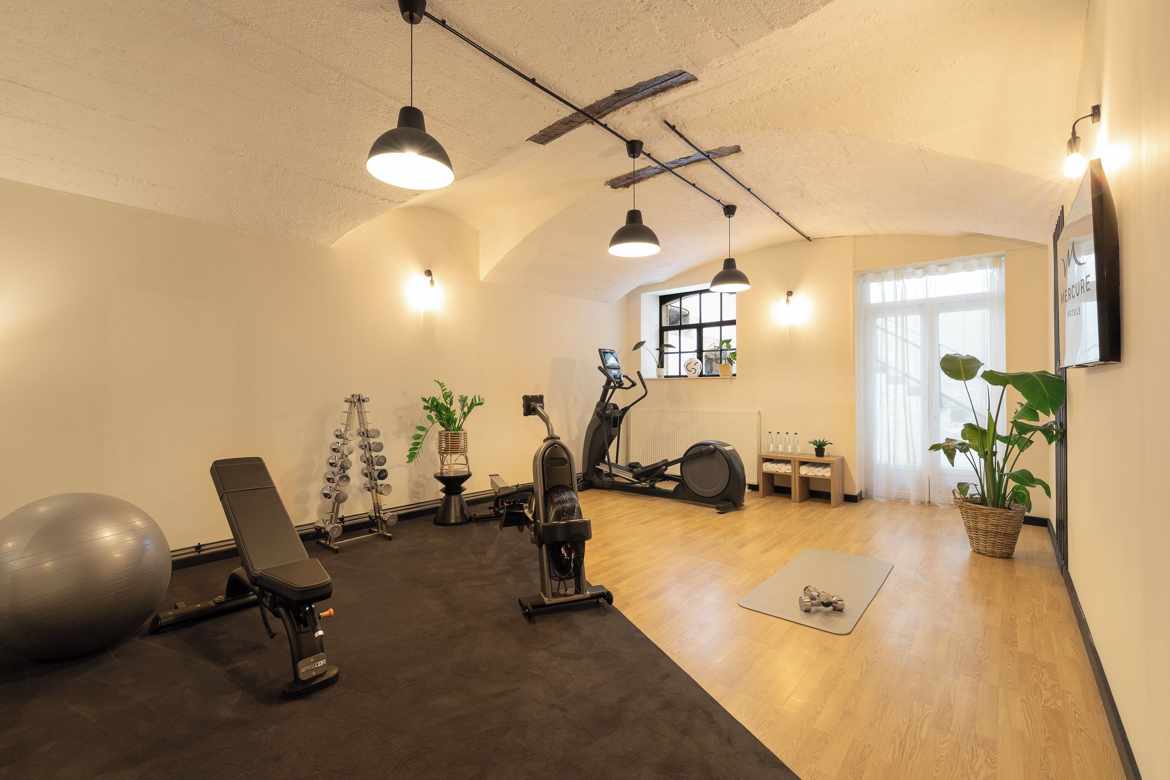 Un gimnasio con equipo de ejercicio, una bicicleta estática y un televisor montado en la pared.