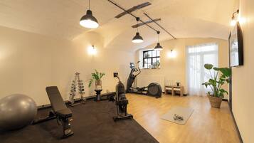 Un gimnasio con equipo de ejercicio, una bicicleta estática y un televisor montado en la pared.