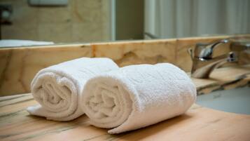 Two rolled towels on a wooden surface, likely in a bathroom setting.