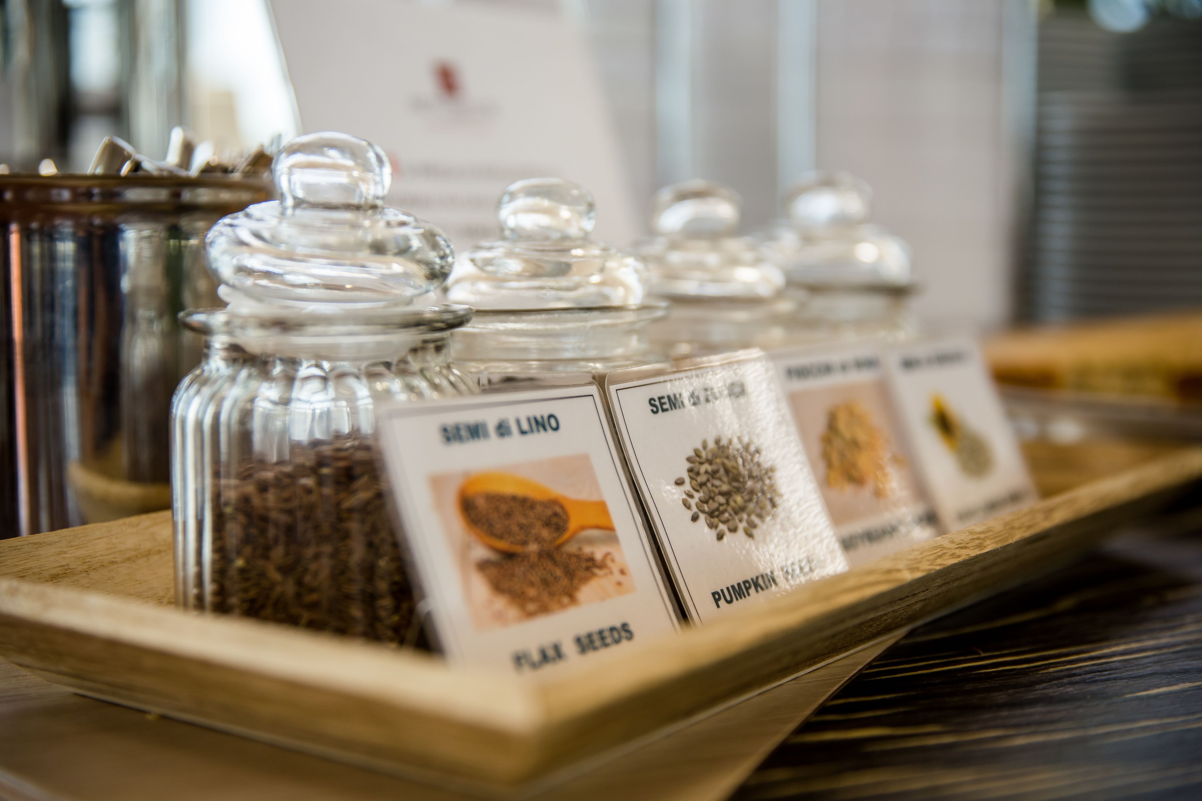 Des bocaux en verre, étiquetés, disposés sur un plateau en bois.
