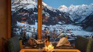 Una mesa de comedor con vistas a montañas nevadas y un pueblo en la falda.