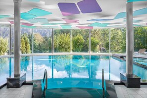 Relax by the pool surrounded by a forest view through large windows.