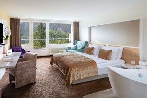 Relax in a spacious room with a large bed, seating area, and forest view.