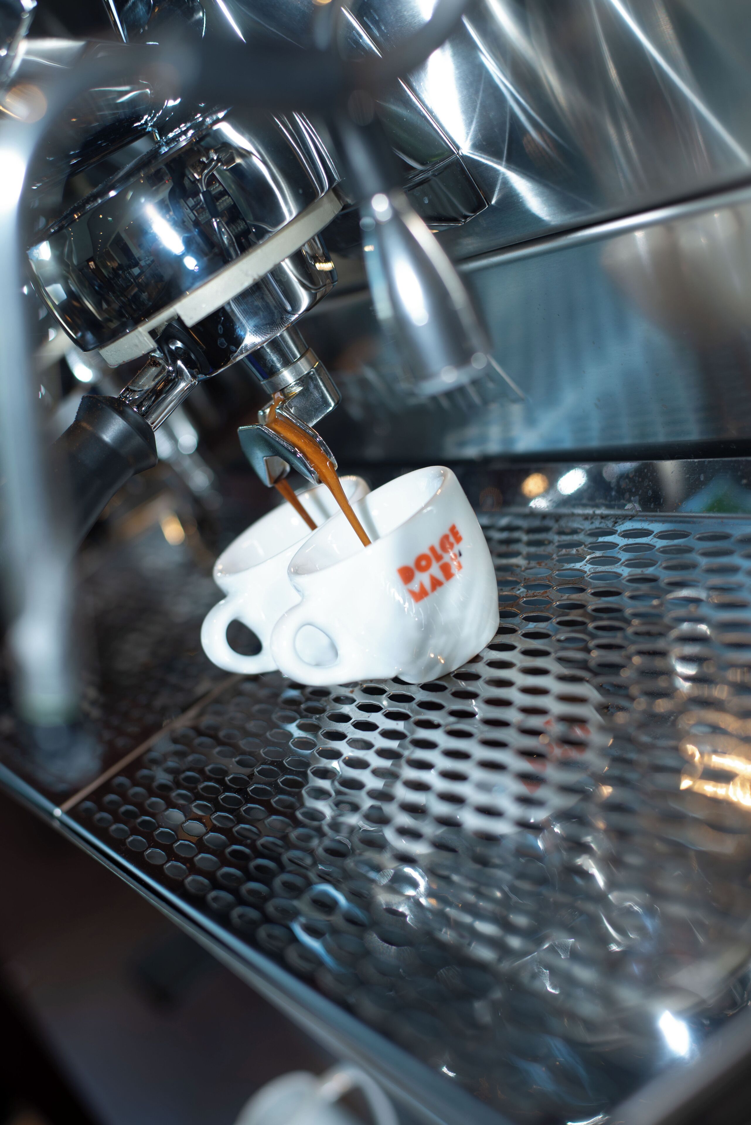 Una macchina per caffè che eroga espresso in una tazza con la scritta 'DOLCE & GABBANA'.