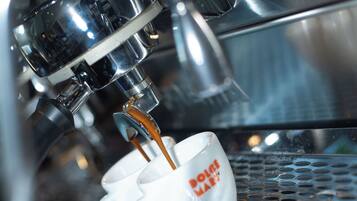 Una macchina per caffè che eroga espresso in una tazza con la scritta 'DOLCE & GABBANA'.