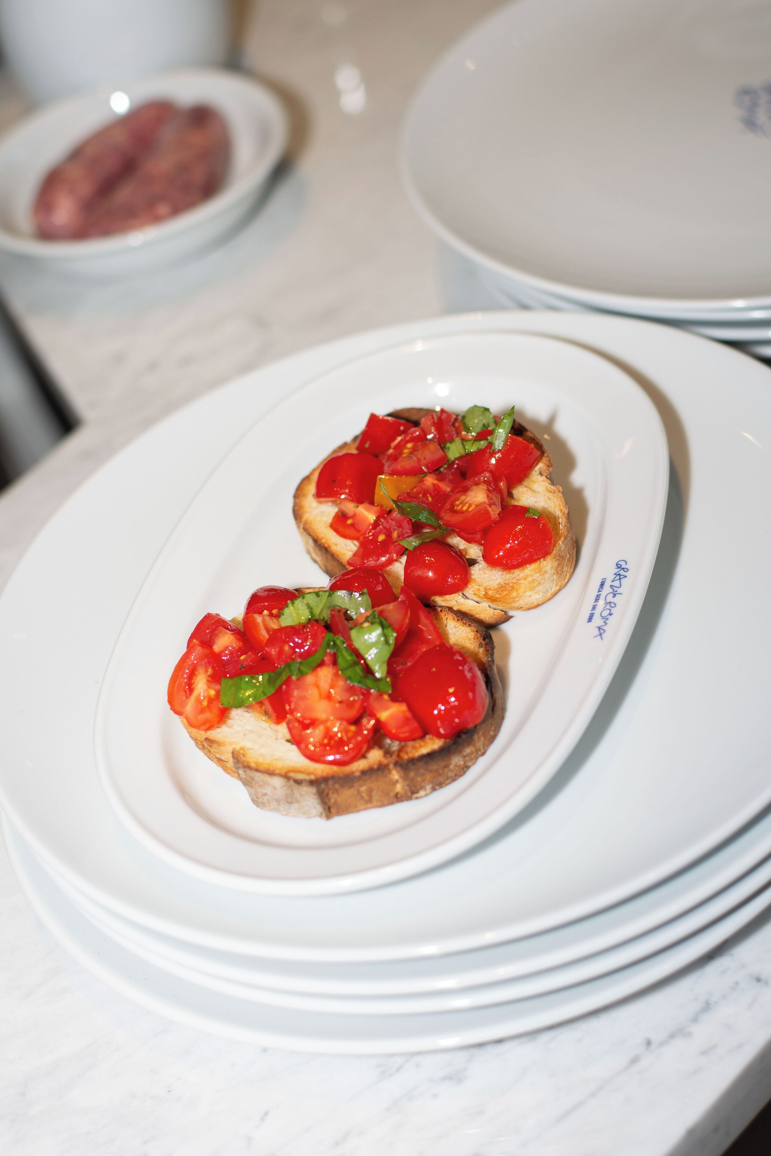 Un plato de bruschetta cubierto de tomates y albahaca.