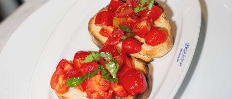 Un plato de bruschetta cubierto de tomates y albahaca.