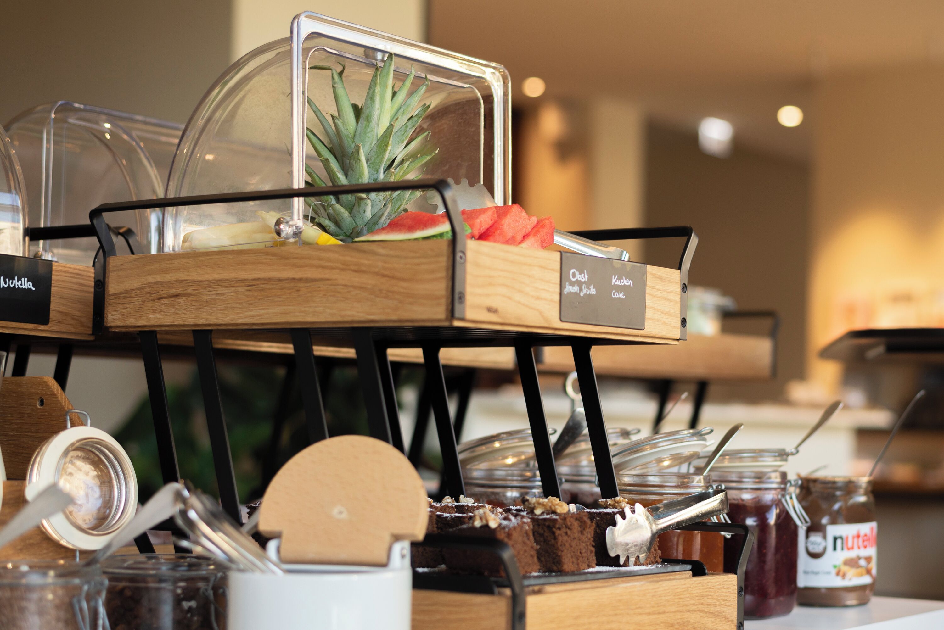 Montaje de bufé con recipientes de vidrio transparente, tablas de madera para servir y diversas opciones de comida.