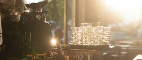 A coffee machine, stacked glasses, and a tray of cups in a cafe setting.