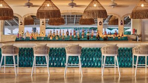 A bar area with a long counter, multiple stools, and hanging rattan lamps. - Fairmont Royal Pavilion (Holetown)
