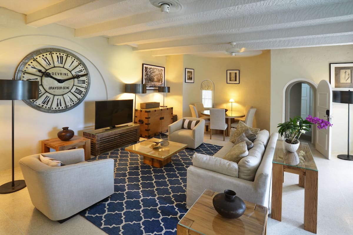 Ein modernes Wohnzimmer mit einer großen Wanduhr, Sofas, einem Couchtisch und einem Fernseher.