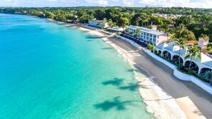 A coastal hotel with a beachfront view, a pool area, and a restaurant with outdoor seating. - Fairmont Royal Pavilion (Holetown)