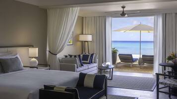 Een hotelkamer met een groot bed, een slaapbank, een kleine tafel en een balkon met uitzicht op de oceaan.